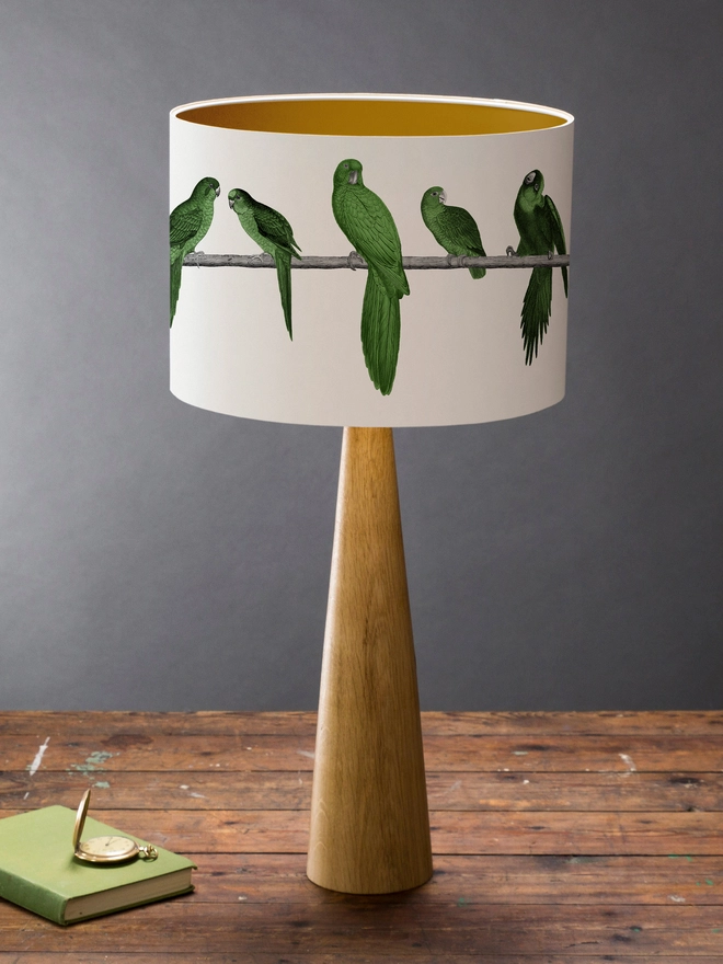 A colourful lampshade featuring a lively group of green parrots in a tropical jungle-inspired design, bringing a playful touch to home interiors.