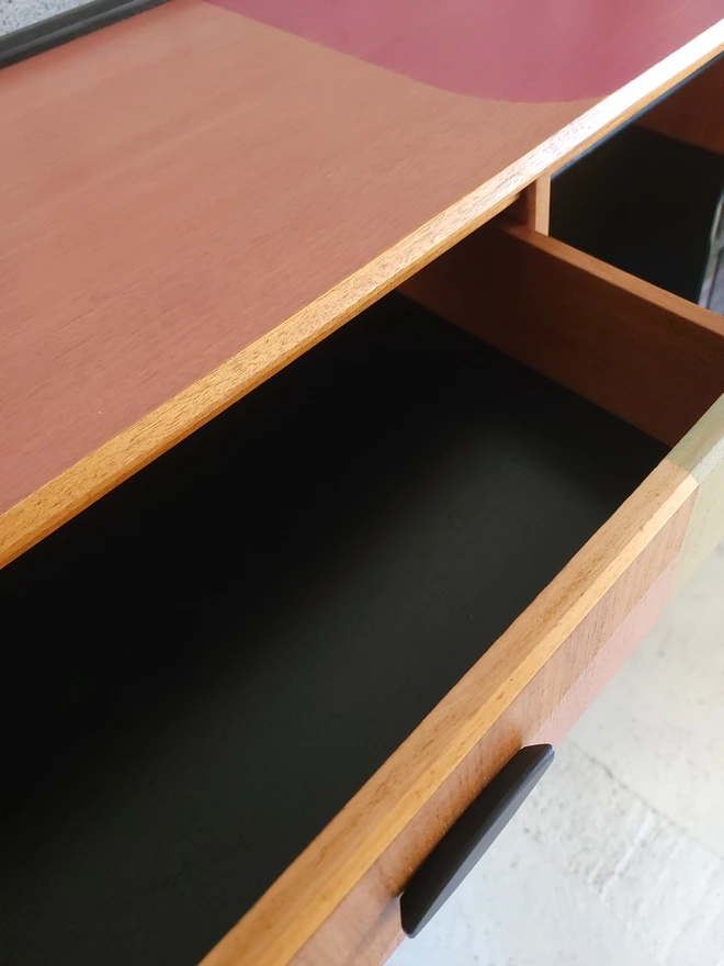 Inside drawer of a teak pink sideboard painted black