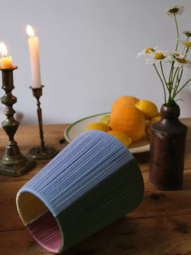 Lifestyle image of quarter colourblock lampshade on table with candle, fruit and flowers