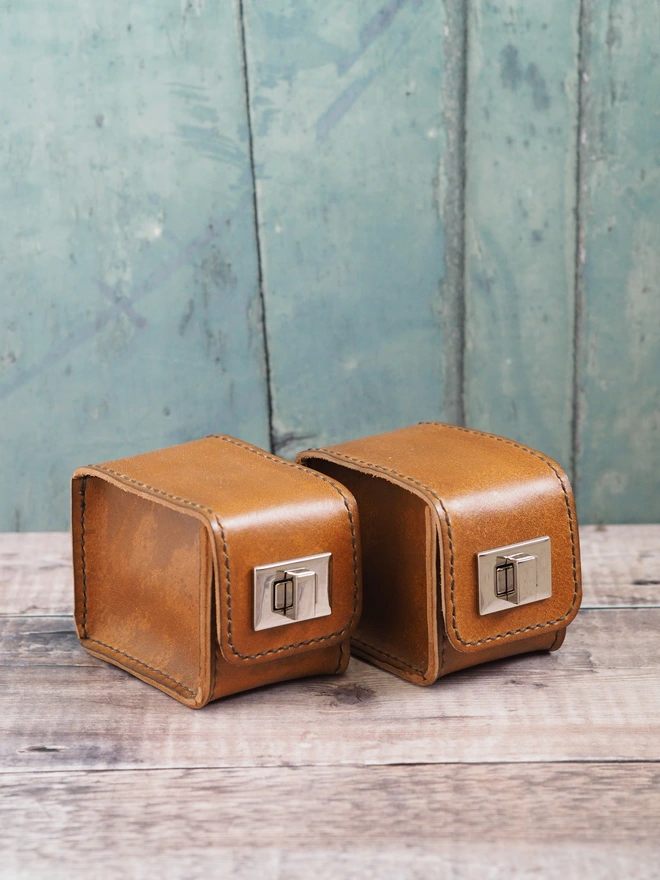 Handmade tan brown leather watch cases with silver metal turn lock clasps.