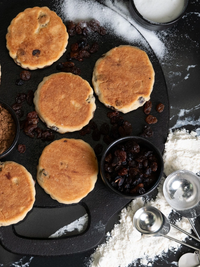 Traditional Hand Made Welsh Cakes on a girddle bakestone with ingredients 