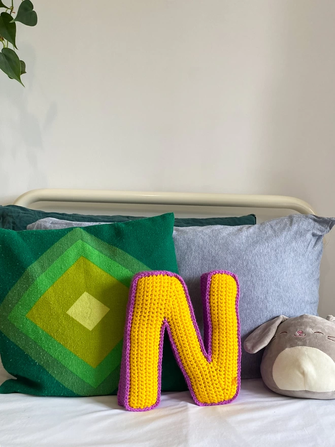 Crocheted N Cushion in Sunshine Yellow & Magenta, on bed
