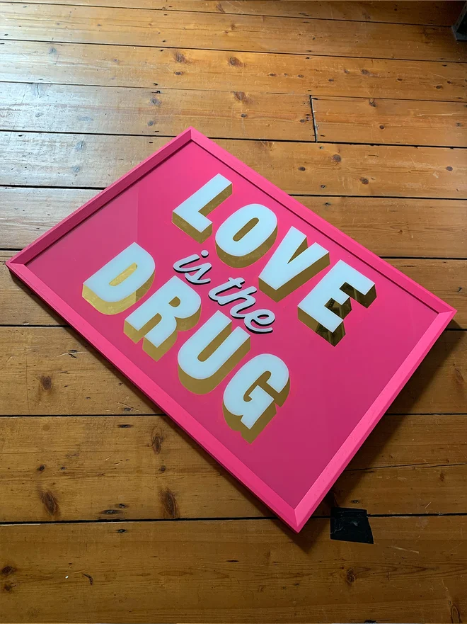 pink and gold love is the drug sign