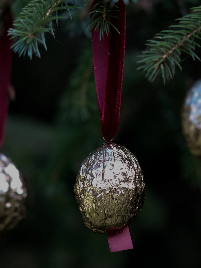 Handmade walnut Christmas ornament with delicate gold gilding, showing the natural shape and grain of the wood. A traditional, nostalgic Christmas tree decoration with timeless old-fashioned charm.