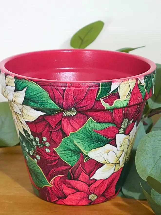 Poinsettia Design Plant Pot seen on a wooden chest.