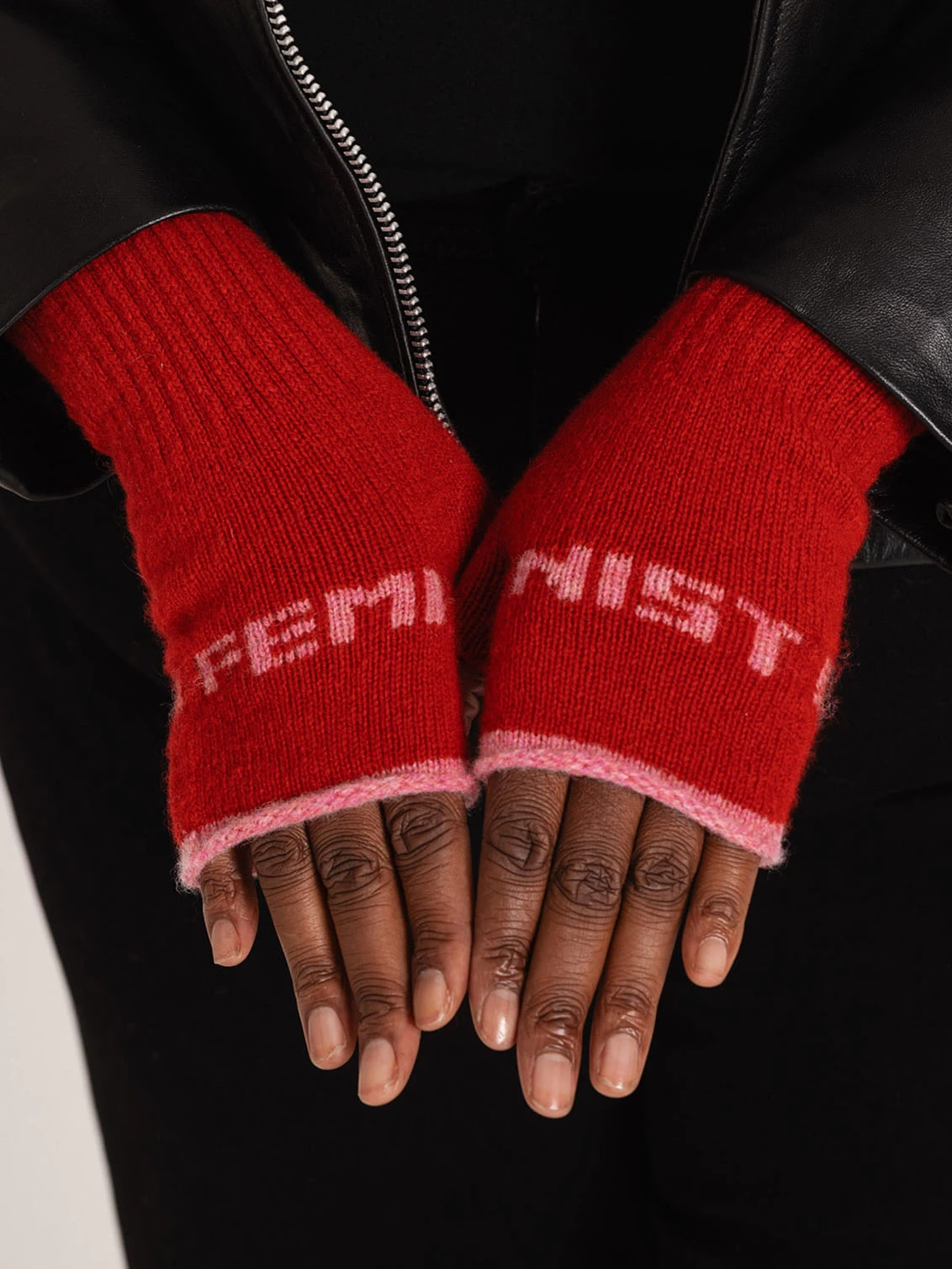 Red feminist mittens on a black womans hands