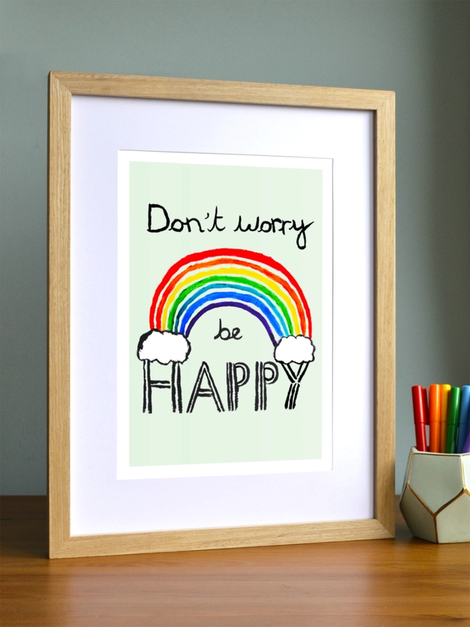 Art print saying 'Don't worry be happy' in a brown frame in a child's room