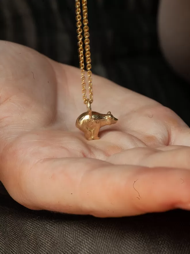 gold polar bear necklace seen on a hand