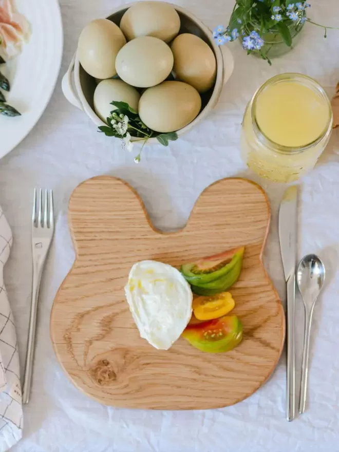Wooden Bunny Serving Board with cheese and tomatoes on the board birds eye view