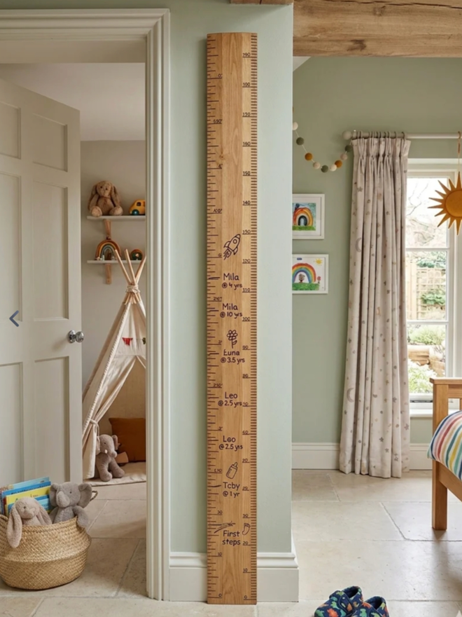 Original Ruler Height Chart. A very large wooden ruler leaning against a wall in a child’s room.