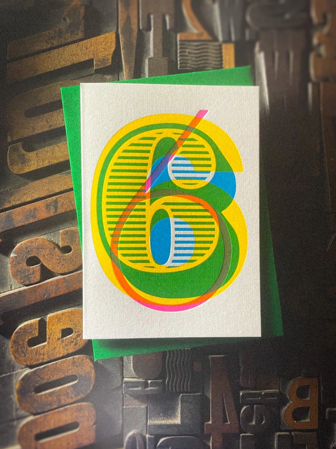 Handmade letterpress 6th birthday card featuring bold overlapping numerals printed in vibrant fluorescent cyan, magenta and yellow inks. Each card is individually hand printed using traditional letterpress techniques on luxury paper stock, creating a beautifully tactile finish with a deep impression and rich layered colours inspired by the CMYK printing process. Printed on a traditional letterpress from 1915.