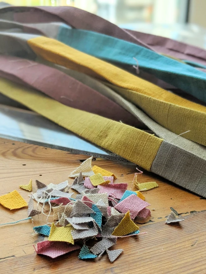 Handmade toy straps in grey and pastel tones, with offcut fabrics shown alongside.