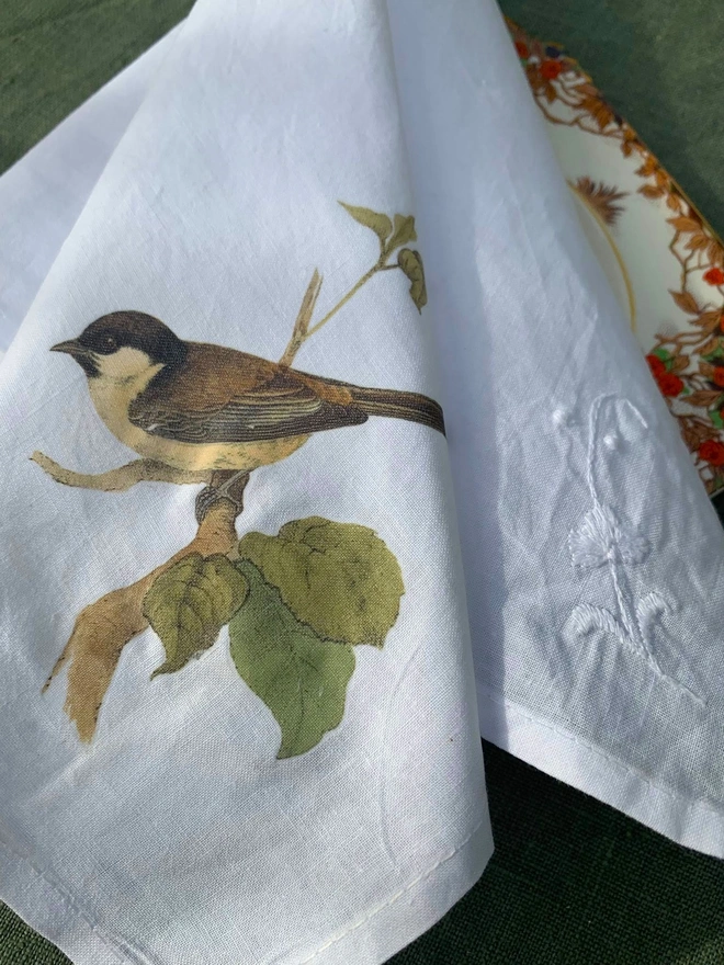 A white cotton napkin printed with a vintage illustration of a sparrow