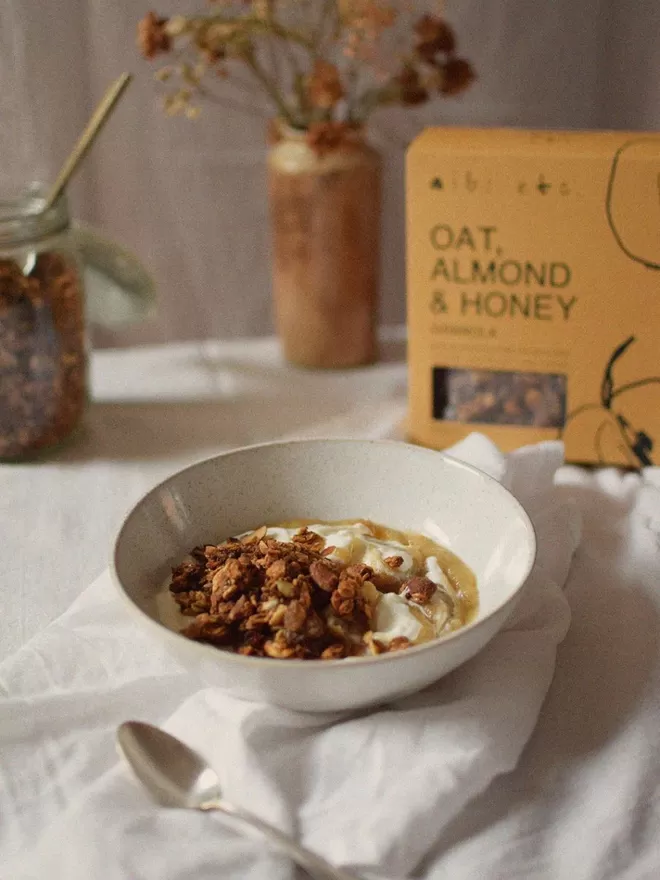 Oat, Almond & Honey Granola In White Bowl With Yoghurt and Spoon