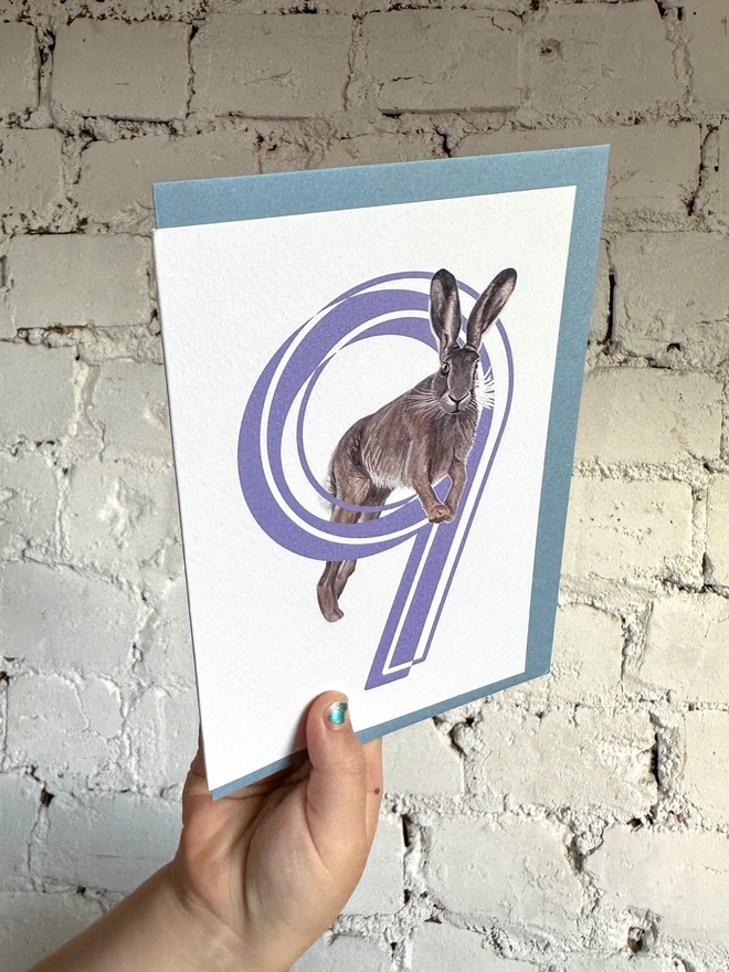 white card with a big purple number 9 and a hare illustration with a blue envelope