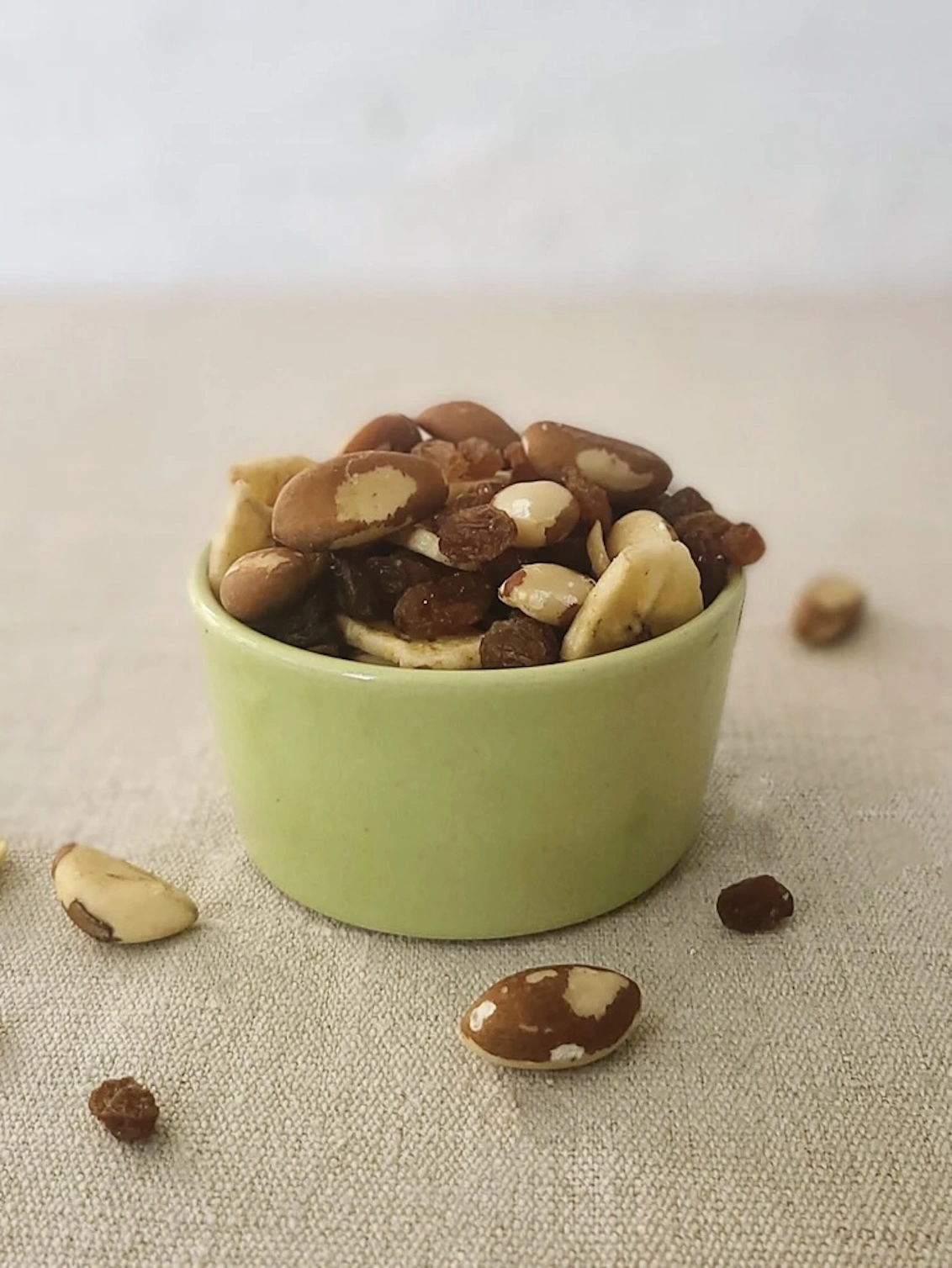 Classic Side Bowl, a colourful ceramic bowl on a wooden surface against a grey backdrop. It is accompanied by some nuts. 