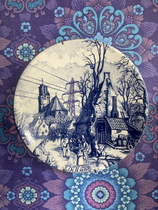 Vintage blue & white Delft plate featuring a winter scene and a pylon.