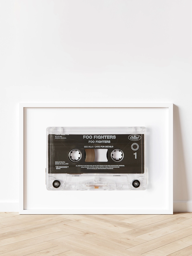 foo fighters cassette tape print. framed print propped up against white wall and wooden floor.
