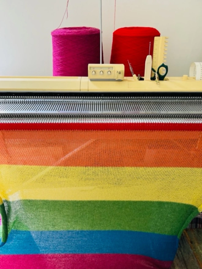 A rainbow blanket shown on the knitting machine
