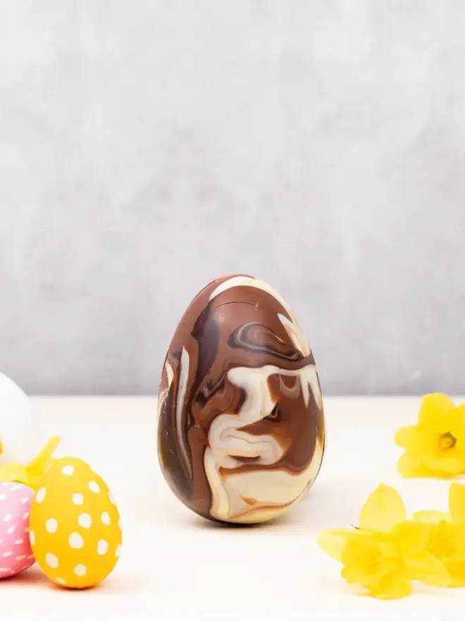 chocolate marbled egg on a table with daffodils 