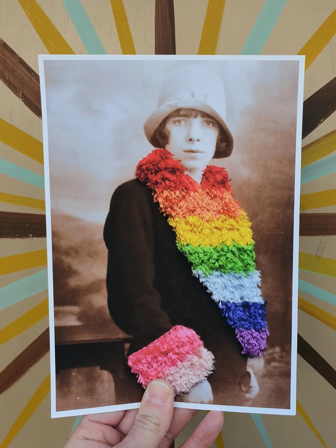  Print of woman wearing embroidered rainbow coloured trim coat held against wall