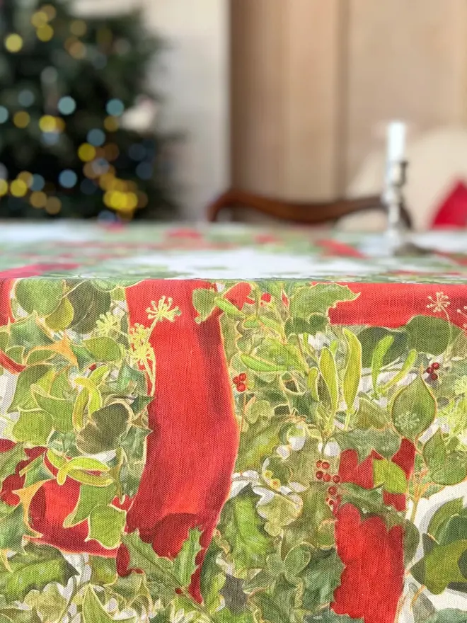 christmas garland lattice tablecloth. a tablecloth printed with holly, ivy and mistletoe on a table.