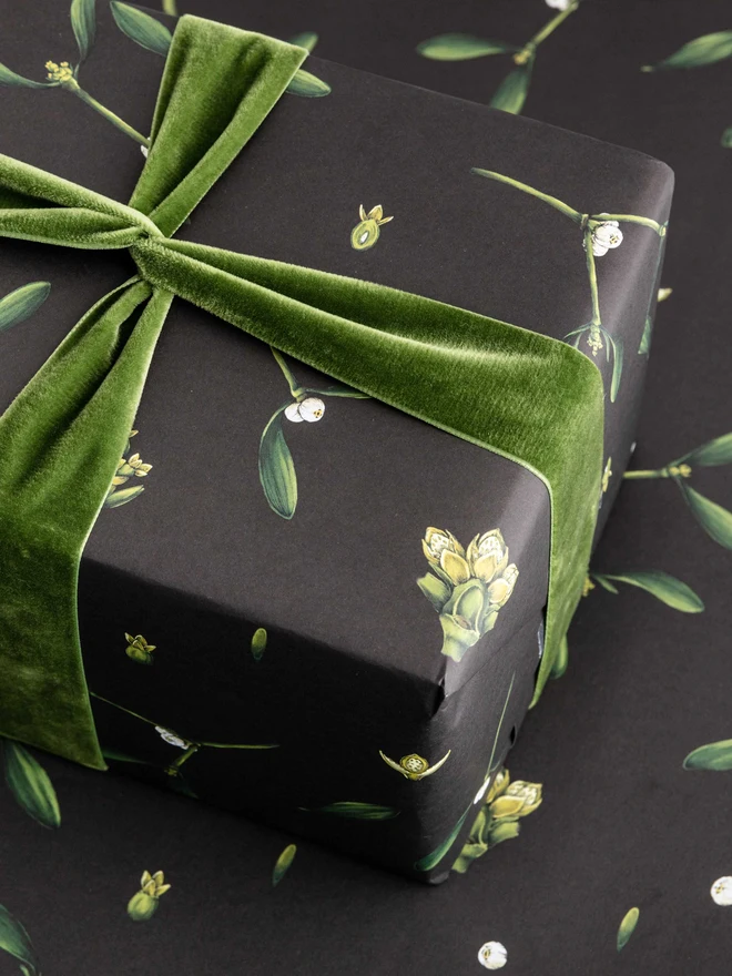 Black based wrapping paper with mistletoe illustration elements