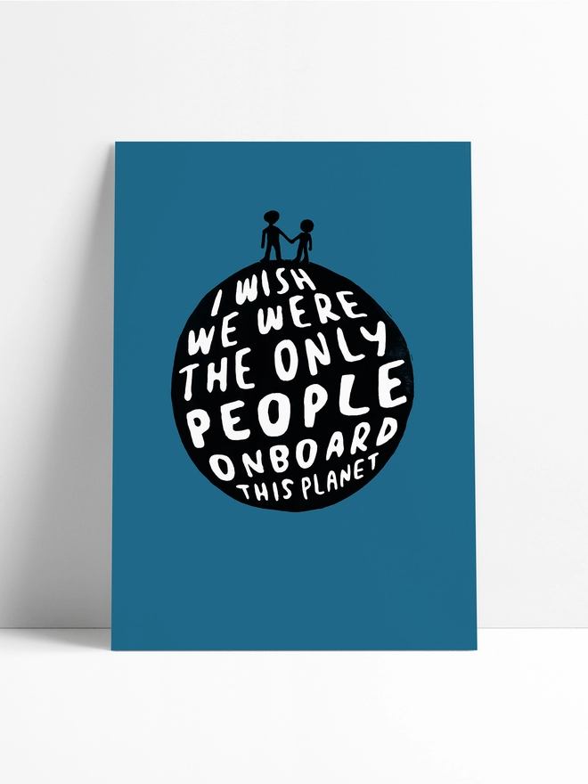 Unframed print leaning against a limbo background, the print has a planet design made from typography, with two little silhouetted people on top. of the planet. The words read: 'I Wish We Were The Only People Onboard This Planet.'  