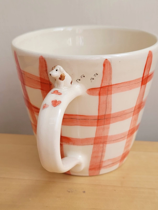 ceramic red gingham check cup with a miniature dog on the handle and red hearts and tiny pawprints on the cup
