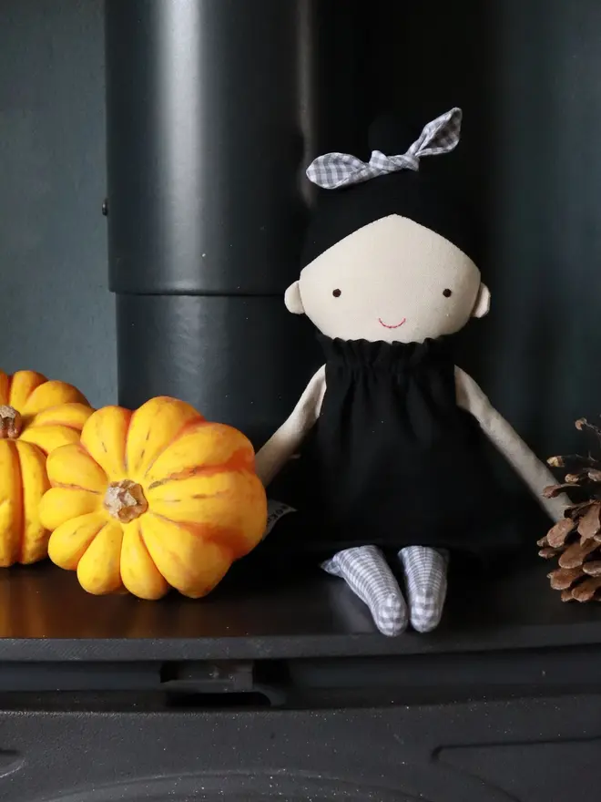marrie top knot girl doll. a linen doll with a black dress and hair tied up with a grey bow.