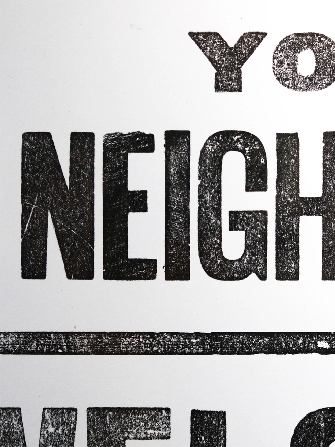 Original letterpress poster featuring the words 'love your neighbour, welcome the stranger' printed in black ink on white paper