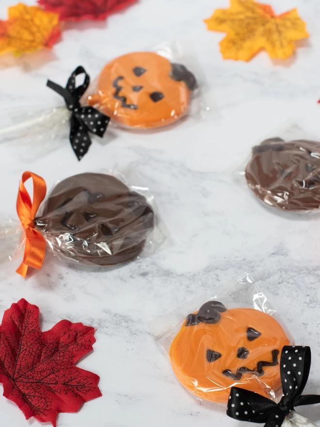 wrapped Orange and milk chocolate pumpkin lollipops surrounded by leaves