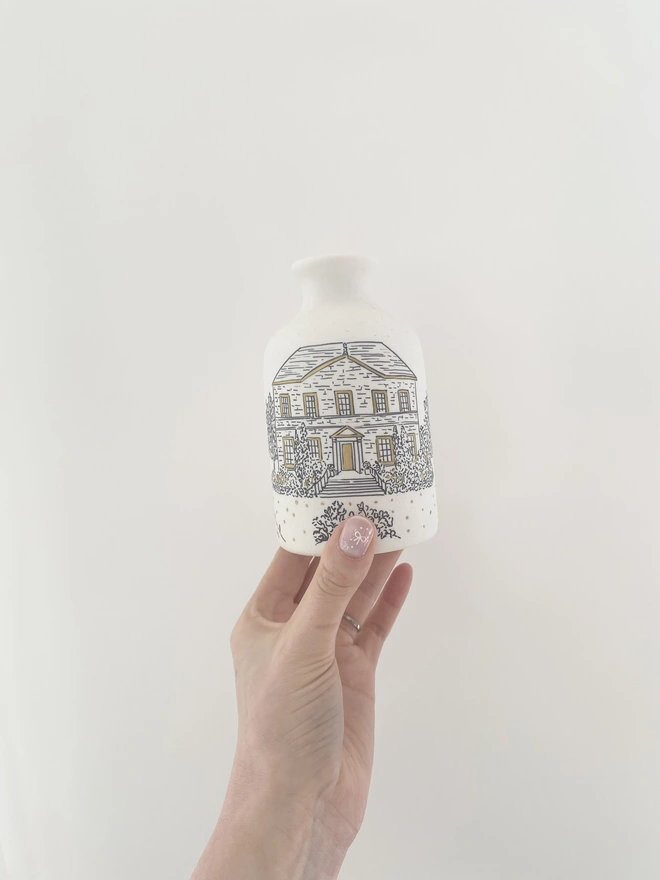 Ceramic vase with a black hand drawn venue illustration and hand painted metallic gold highlights