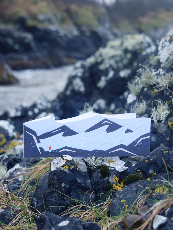 A cut out card of a stormy seascape on top of rocks