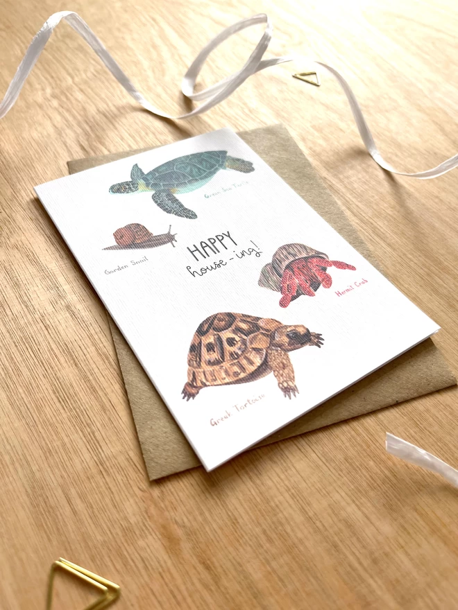 a greetings card featuring four animals who carry their own home with the phrase “happy house-ing”