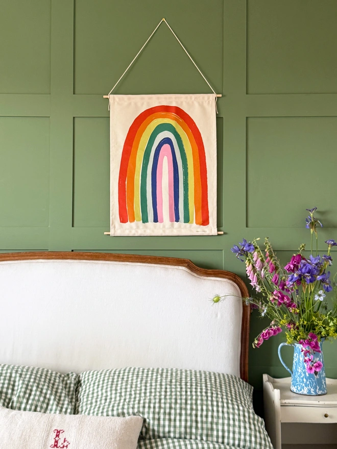 Cotton Bright Rainbow Fabric Banner, against a green wall. 