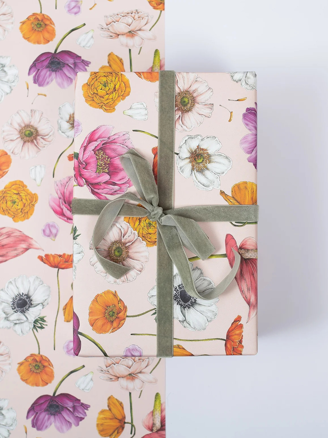 floral brights floral gift wrap sheet. a box wrapped in pale pink illustrated floral gift wrap with a green ribbon.