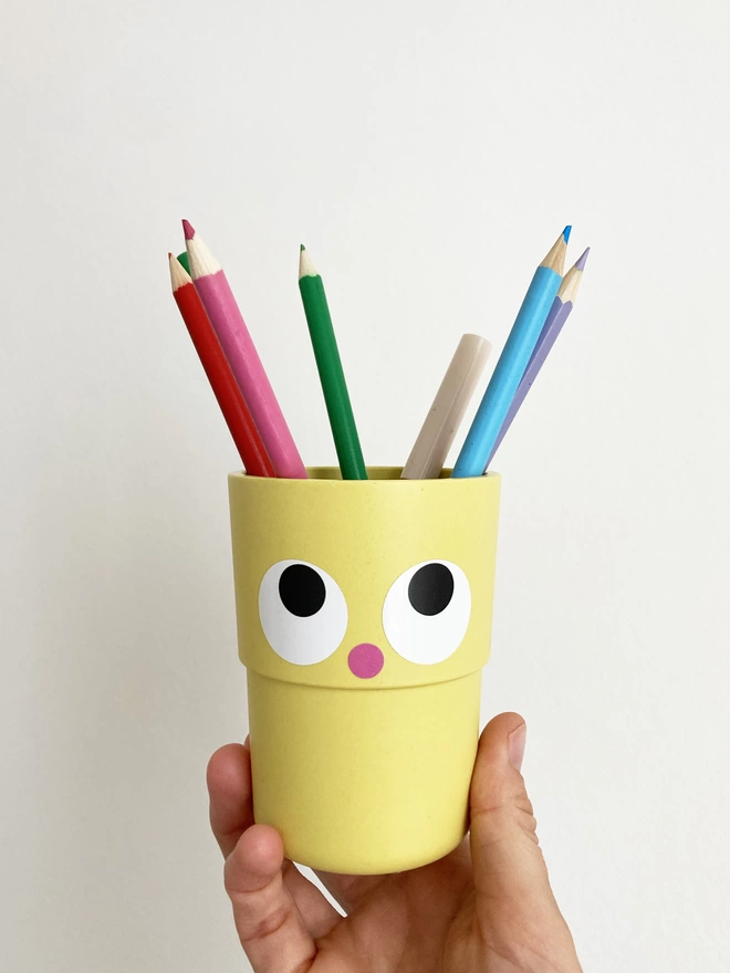 A pen pot customised with eye stickers 