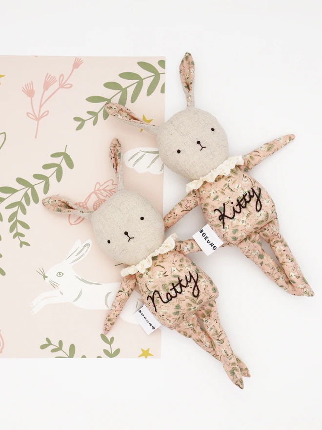 Handmade bunny rabbit dolls in pink floral print and natural linen with frilly cotton lace collar, personalised embroidery on their body. 