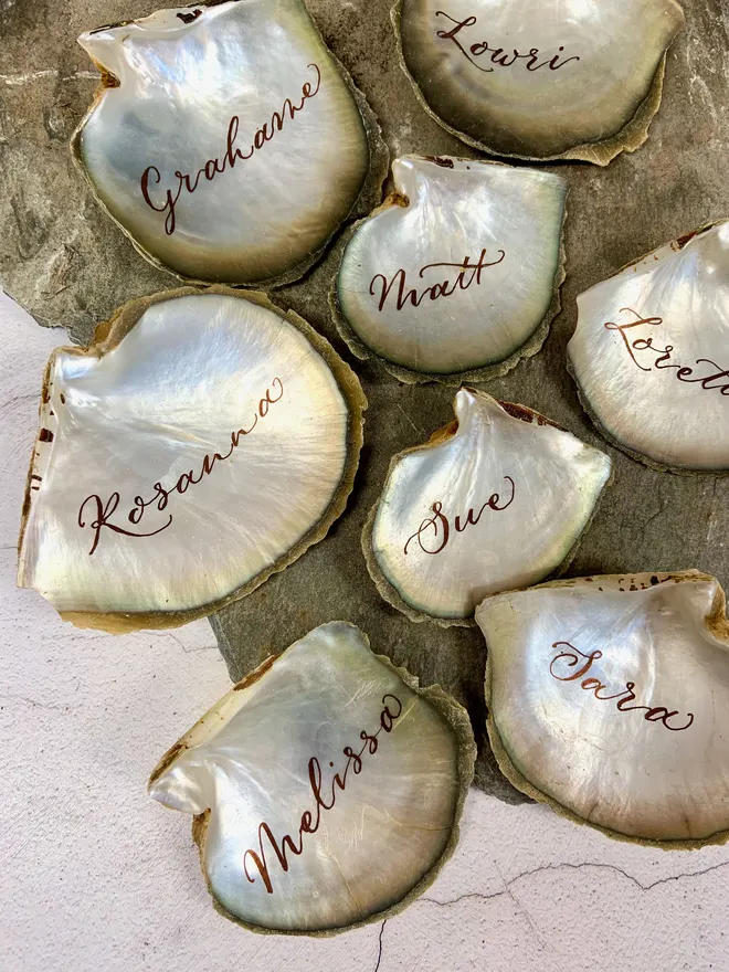 Pearlescent oyster place settings with names written in calligraphy