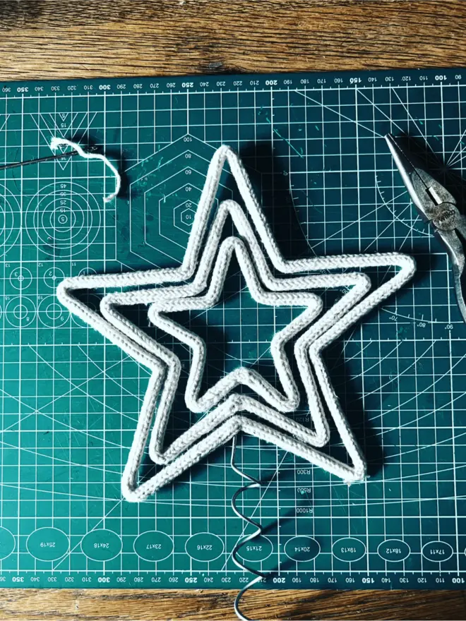 String & wire Triple Star tree topper on a green cutting mat