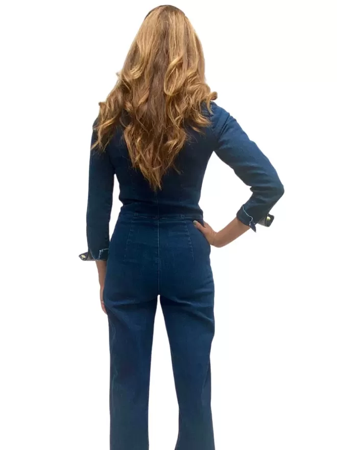 model posing with a hand on her hip back view of the ruby denim jumpsuit