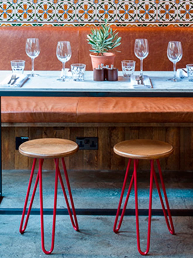 pair of hairpin leg stools with red legs in a tapas restaurant