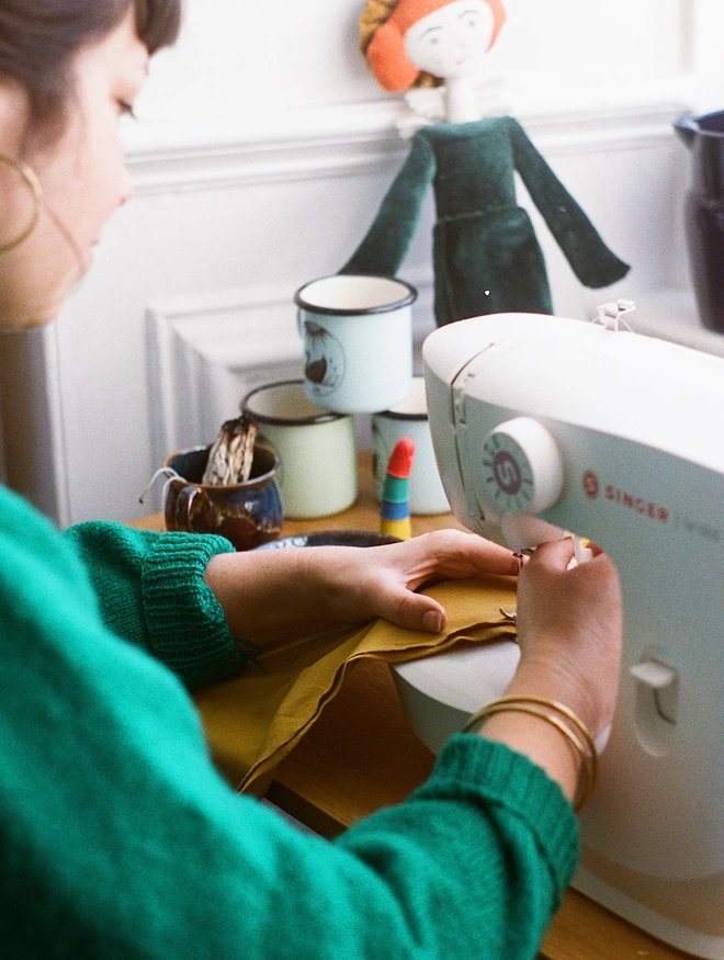 Woman in a green jumper at a sewing machine 