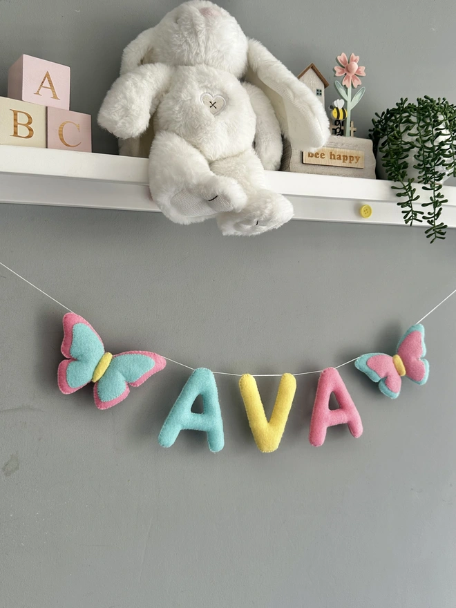 Personalised Name Icon Garland, a child’s name banner  hanging from a white shelf, nursery decoration, baby gift