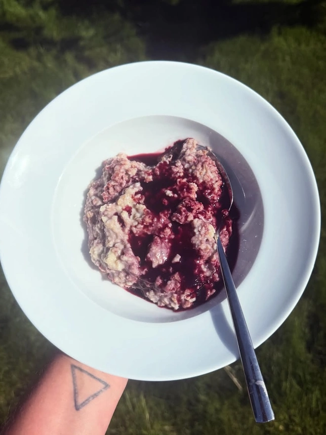 bowl of porridge with dark purple mulberry sauce