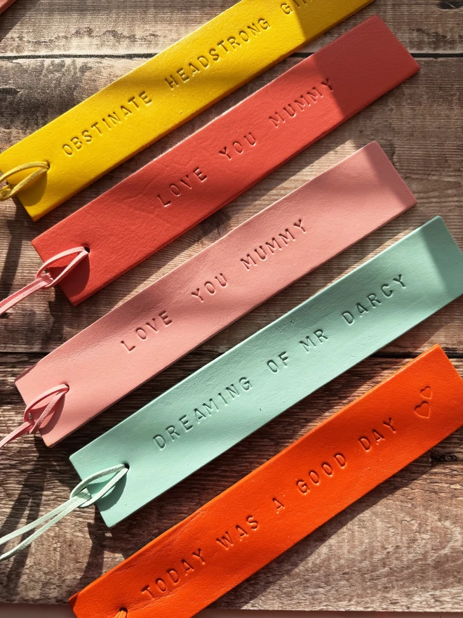 Colourful hand-painted leather bookmarks with embossed quotes, each featuring a leather tie. A stylish and durable accessory for book lovers, perfect as a personalised gift