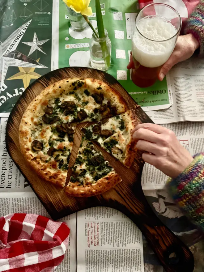 Handmade oak pizza board burnt edges styled with pizza daffodils on newspaper 