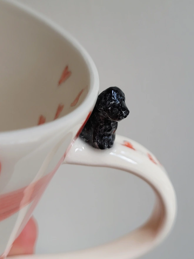 ceramic mug with a tiny black cockerpoo poodle dog on the handle with red hearts and check
