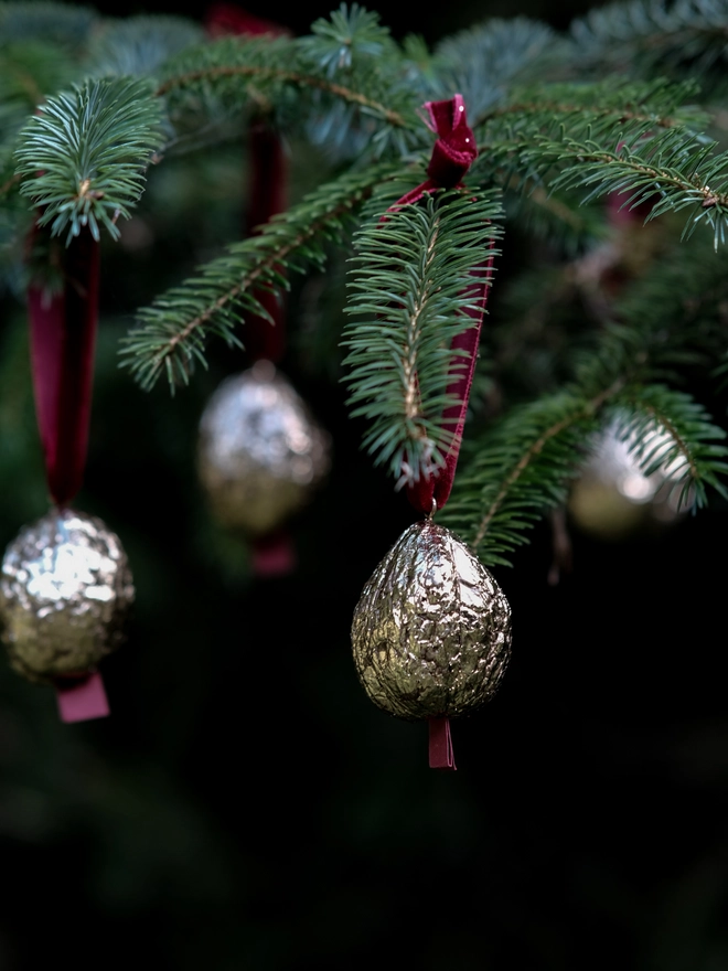 Handmade walnut Christmas ornament with delicate gold gilding, showing the natural shape and grain of the wood. A traditional, nostalgic Christmas tree decoration with timeless old-fashioned charm.